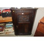 A carved oak wall mounted corner cupboard