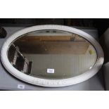 An oval framed bevelled edge wall mirror