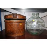 A glass carboy together with a metal hat box