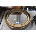 A gilt oval framed and bevelled edge wall mirror