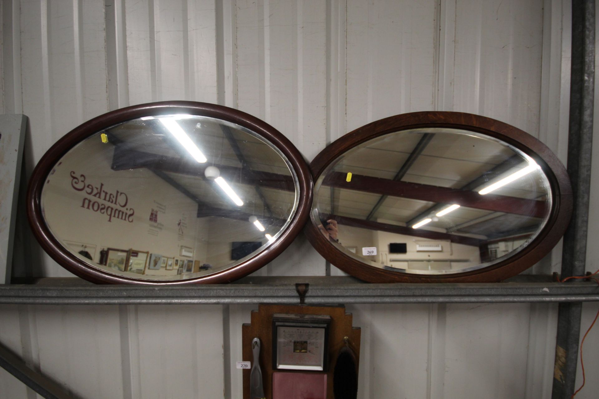 An oak framed oval bevel edged wall mirror; and on