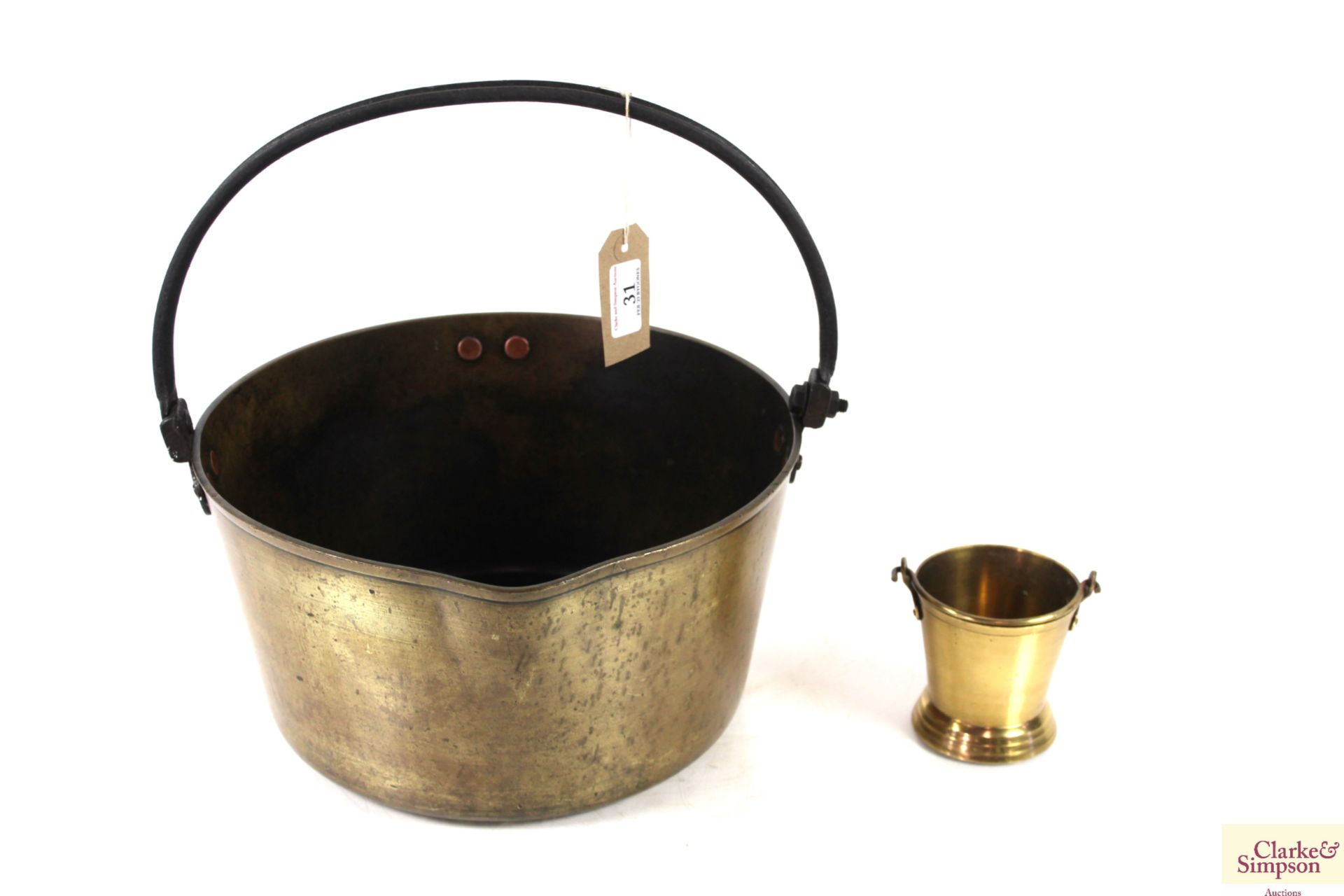 A large brass jam pan with metal swing handle and