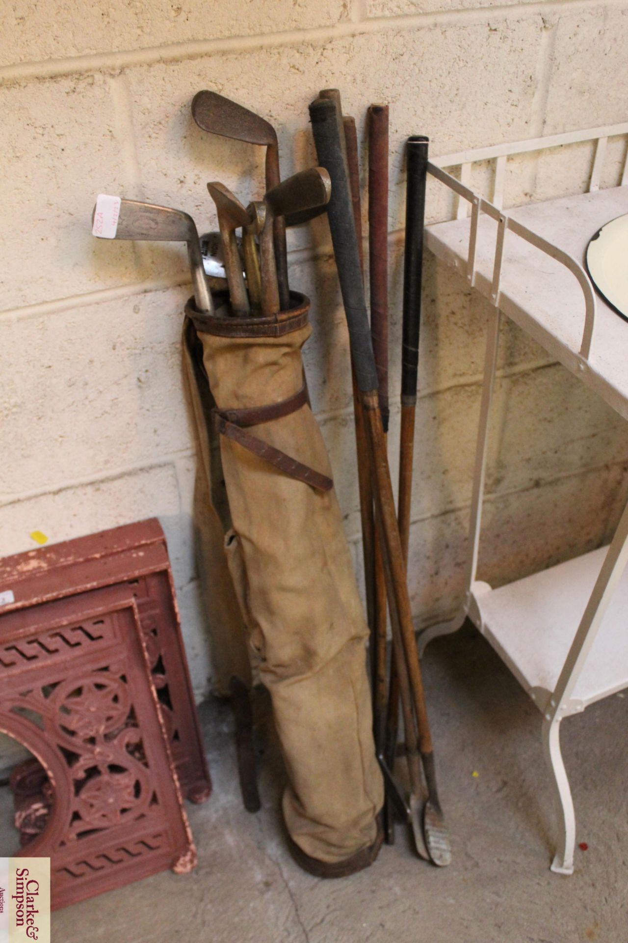 A vintage canvas and leather golf bag and a quantity of vintage hickory shafted golf clubs