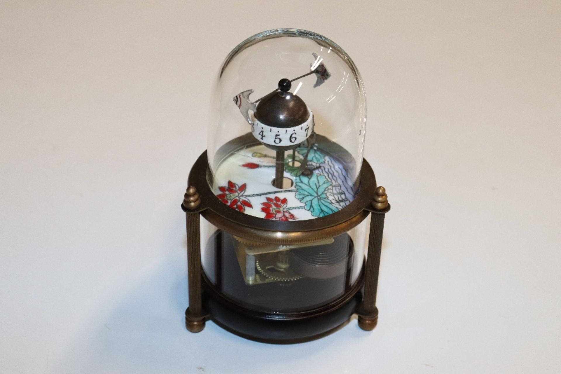 A novelty clock decorated with fish under dome