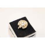 A boxed white metal flower head ring