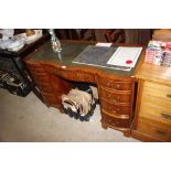 A green leather topped serpentine fronted desk, fi