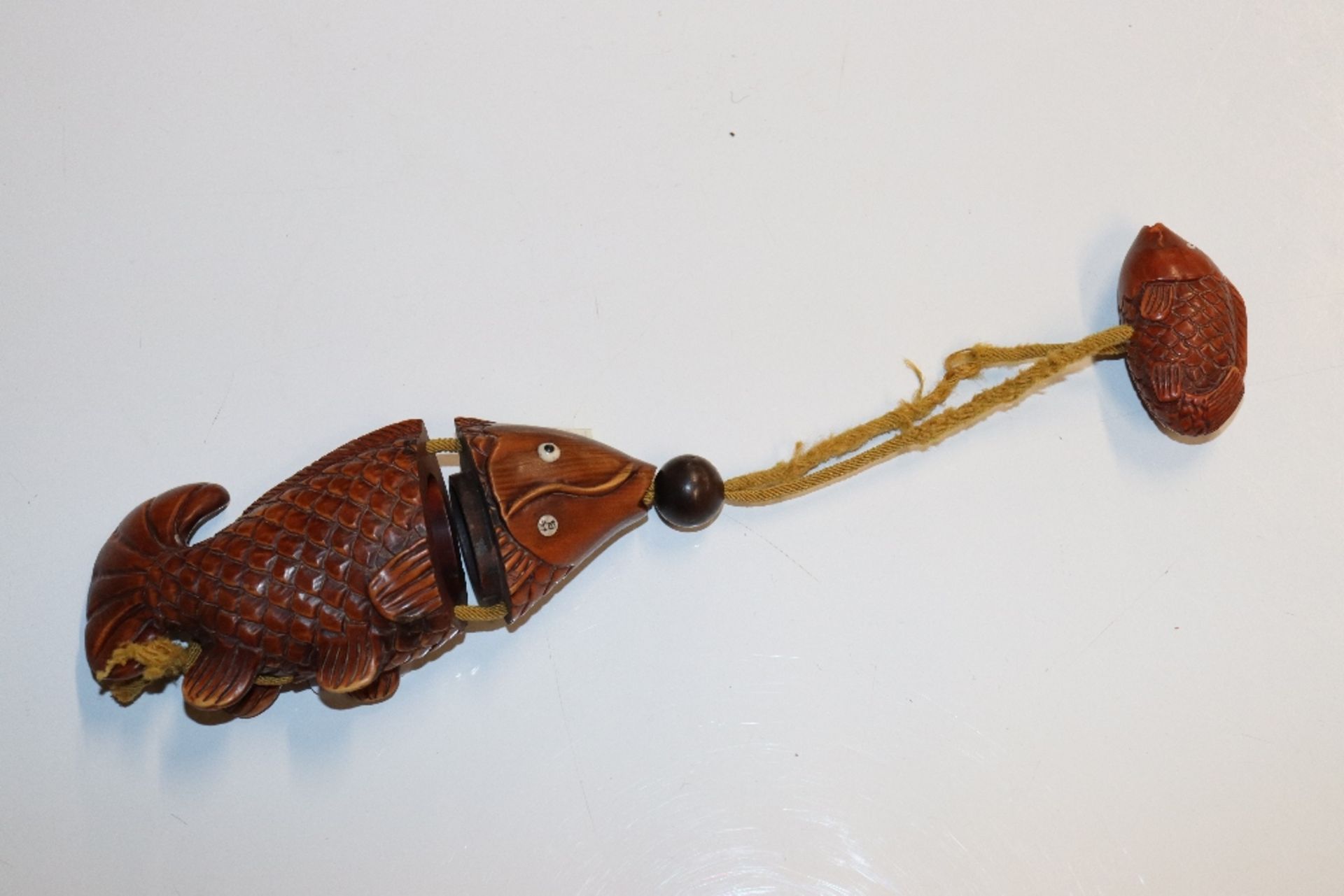 A carved wooden fish inro