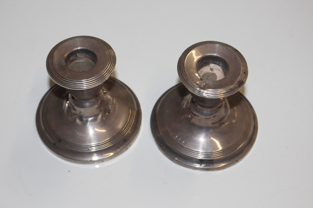 A pair of silver dwarf candlesticks with loaded ba
