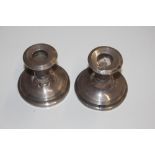 A pair of silver dwarf candlesticks with loaded ba