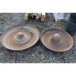 Two circular cast iron pig troughs