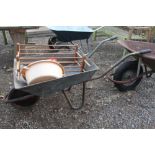 A galvanised wheelbarrow; petrol can; wash bowl et