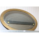 A gilt oval framed and bevelled edge wall mirror