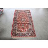 An approximately 5'2" x 2'8" red patterned rug