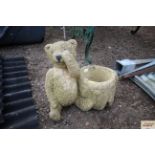 A garden ornament in the form of a teddy bear and decorated tree stump pot