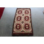 An approx. 4'4" x 2'4" brown and red patterned rug