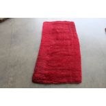 An approx. 4'6" x 2'4" red patterned rug