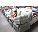 A green upholstered set of three armchairs and mat