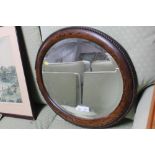 An oak framed and bevel edged oval wall mirror