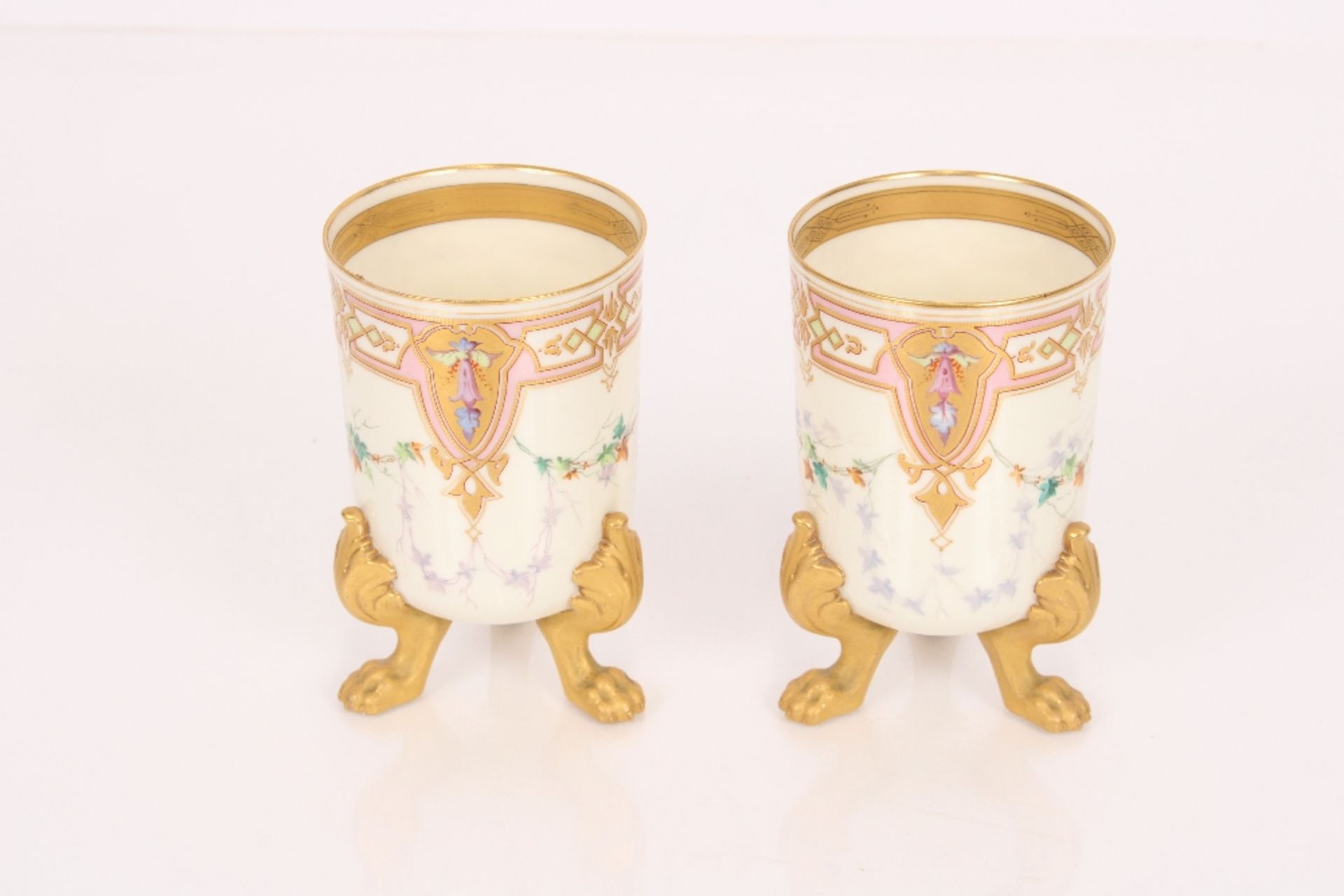 A pair of porcelain beaker vases raised on gilt cl