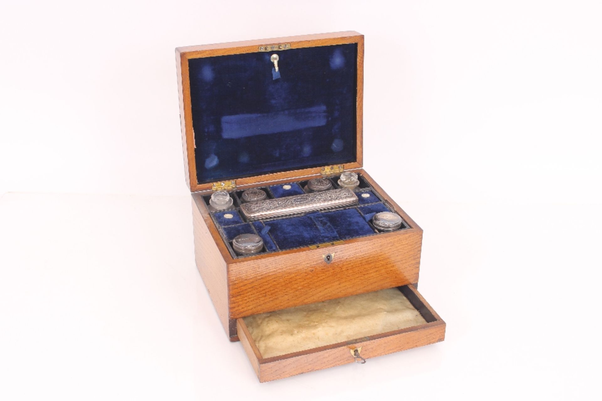 A 19th century golden oak, cased vanity box containing various bottles and tidy jars with foliate