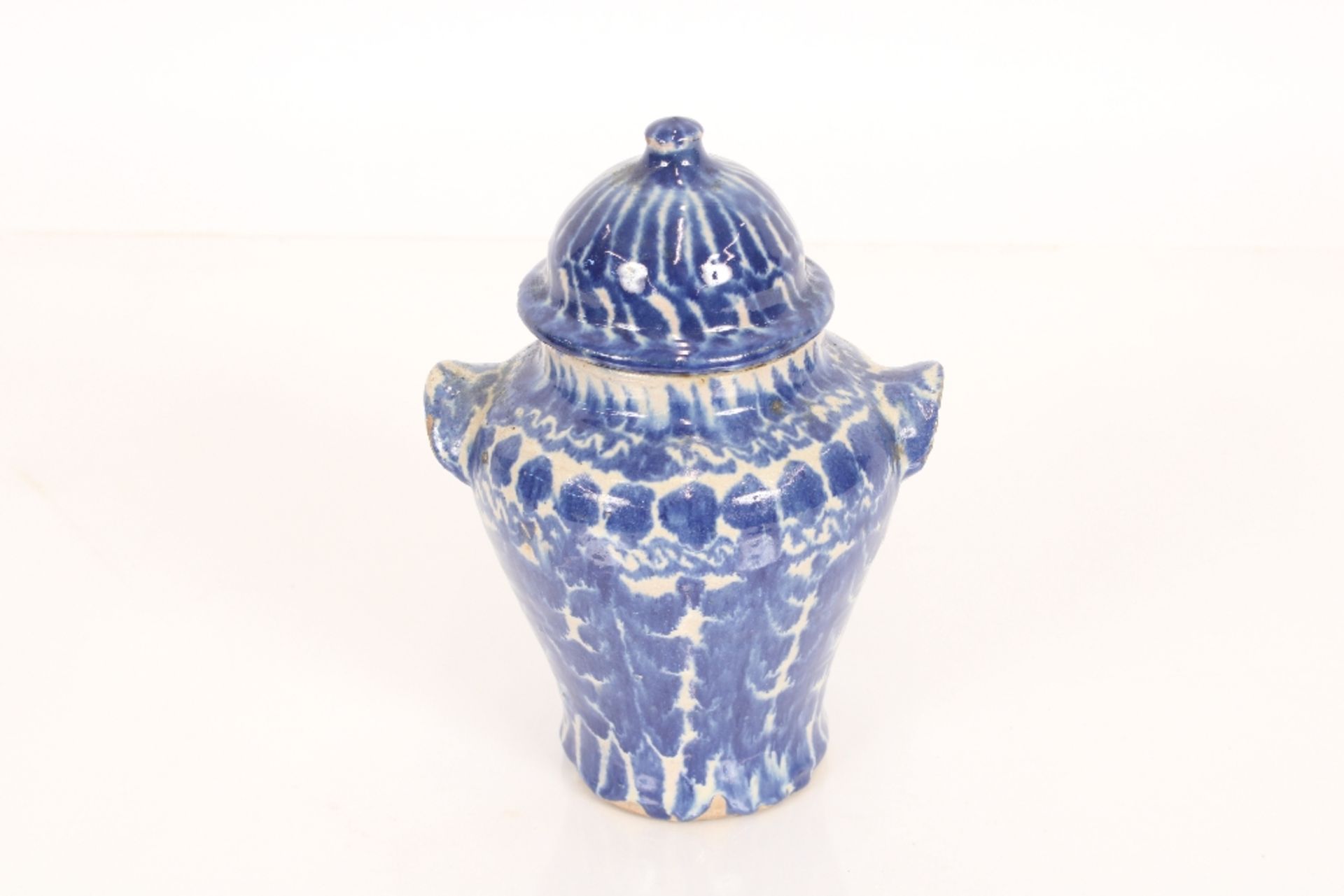 A Middle Eastern pottery vase and cover of baluster form with blue sponge decoration, 21cm high