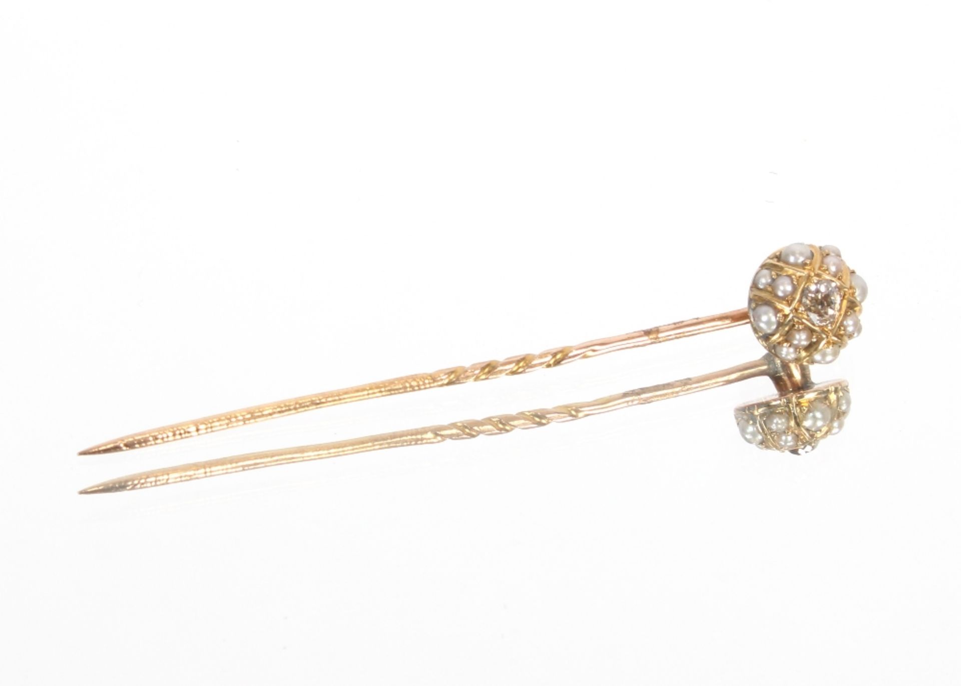 A yellow metal stick pin set with diamonds, surrou