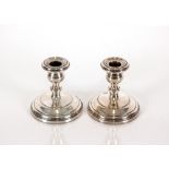 A pair of white metal dwarf candlesticks with load