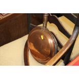 A copper bed warming pan with turned handle