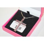 A silver and pink crystal crucifix pendant hung to