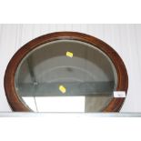 An oak framed circular bevelled edge wall mirror