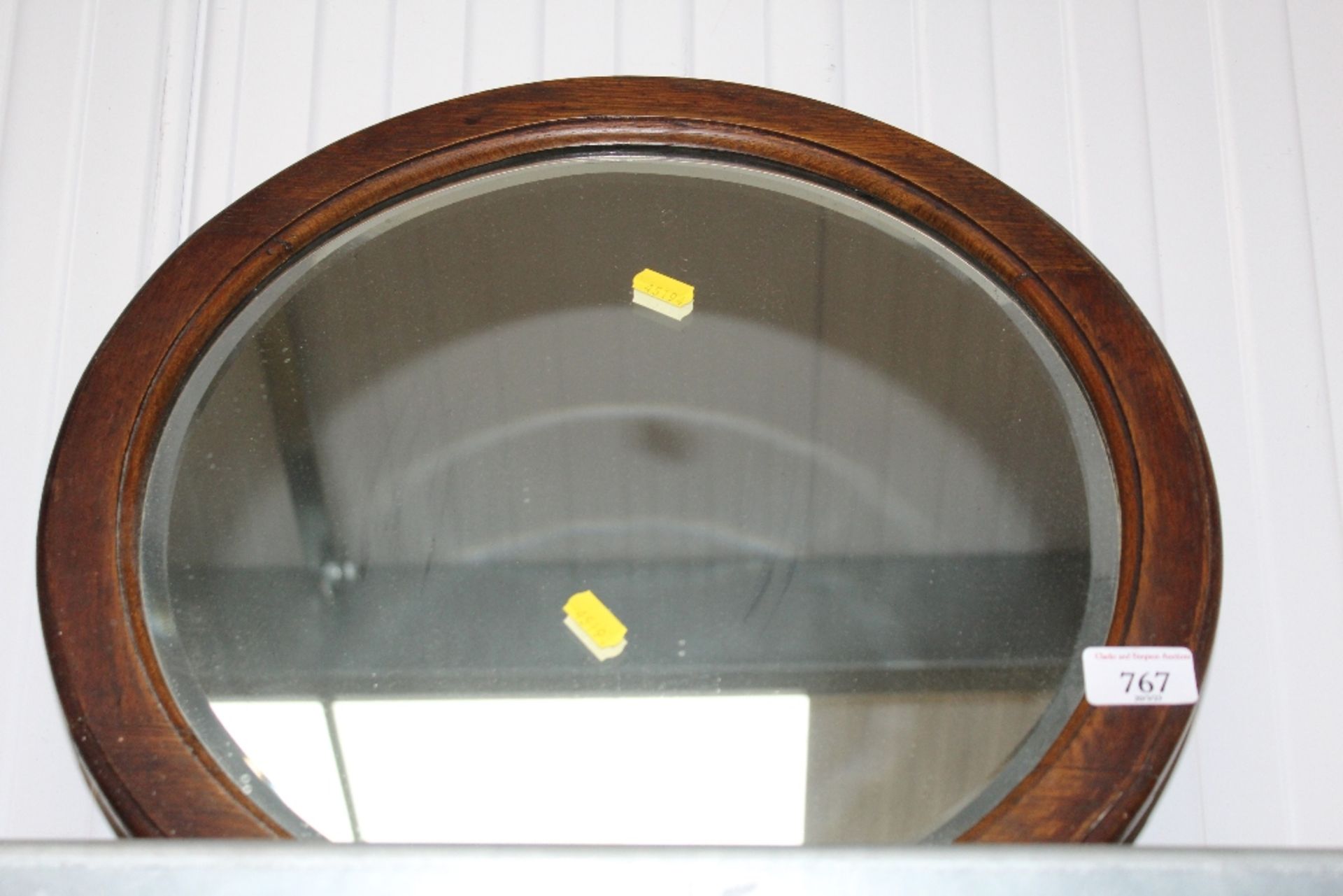 An oak framed circular bevelled edge wall mirror