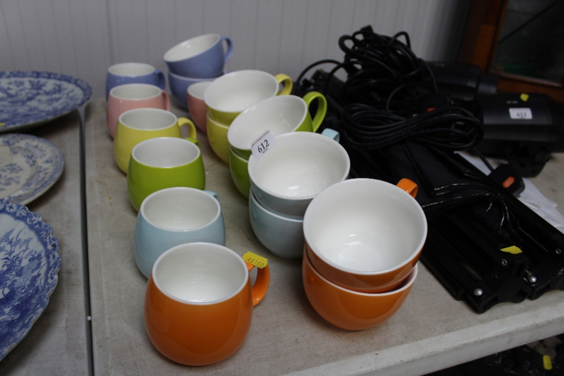 A quantity of coloured mugs