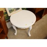 A circular white painted coffee table raised on ca
