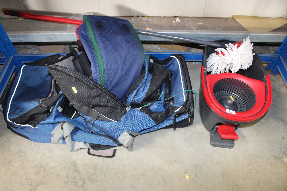 A suitcase and a bag together with a mop and bucke