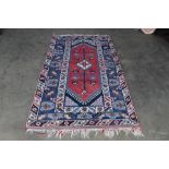 An approx. 7'2" x 3'11" blue and red patterned rug