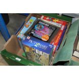 A box of various jigsaw puzzles and games