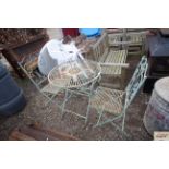 An ornate metal folding garden table and two match