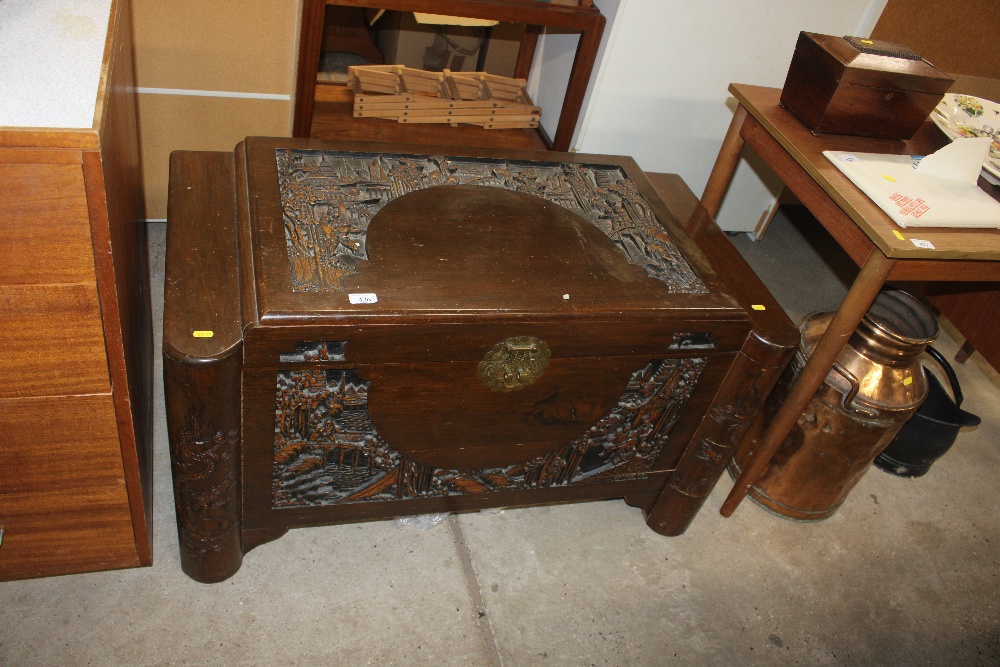 A Chinese carved camphor wood blanket box with rel