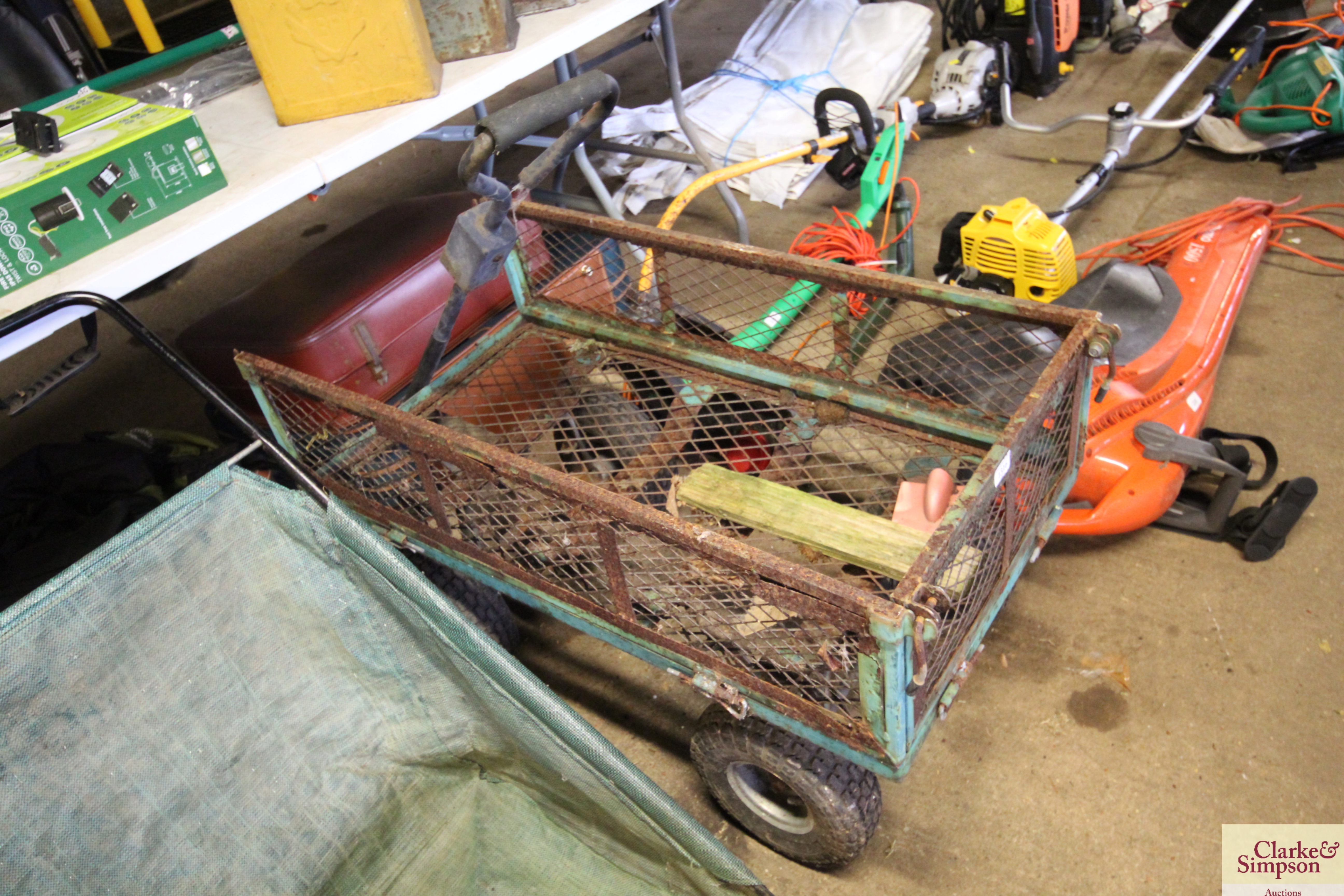 A four wheeled metal garden trolley with drop side