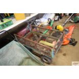 A four wheeled metal garden trolley with drop side