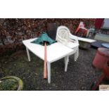 A white plastic garden table with four matching ch