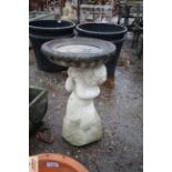 A garden bird bath in the form of a cherub