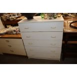 A white laminate chest of five drawers
