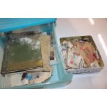 A tin and plastic box of various stamp albums and