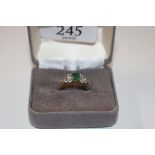 A yellow metal ring marked 14K set with green and