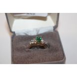 A yellow metal ring marked 14K set with green and