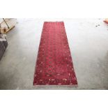 An approx. 9'5" x 2'8" red patterned rug