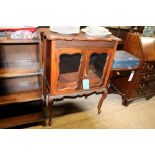 A mahogany glazed side cupboard raised on sabre su