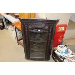 An antique carved oak and glazed corner cabinet