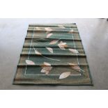 An approx. 5'5" x 4'5" green patterned rug